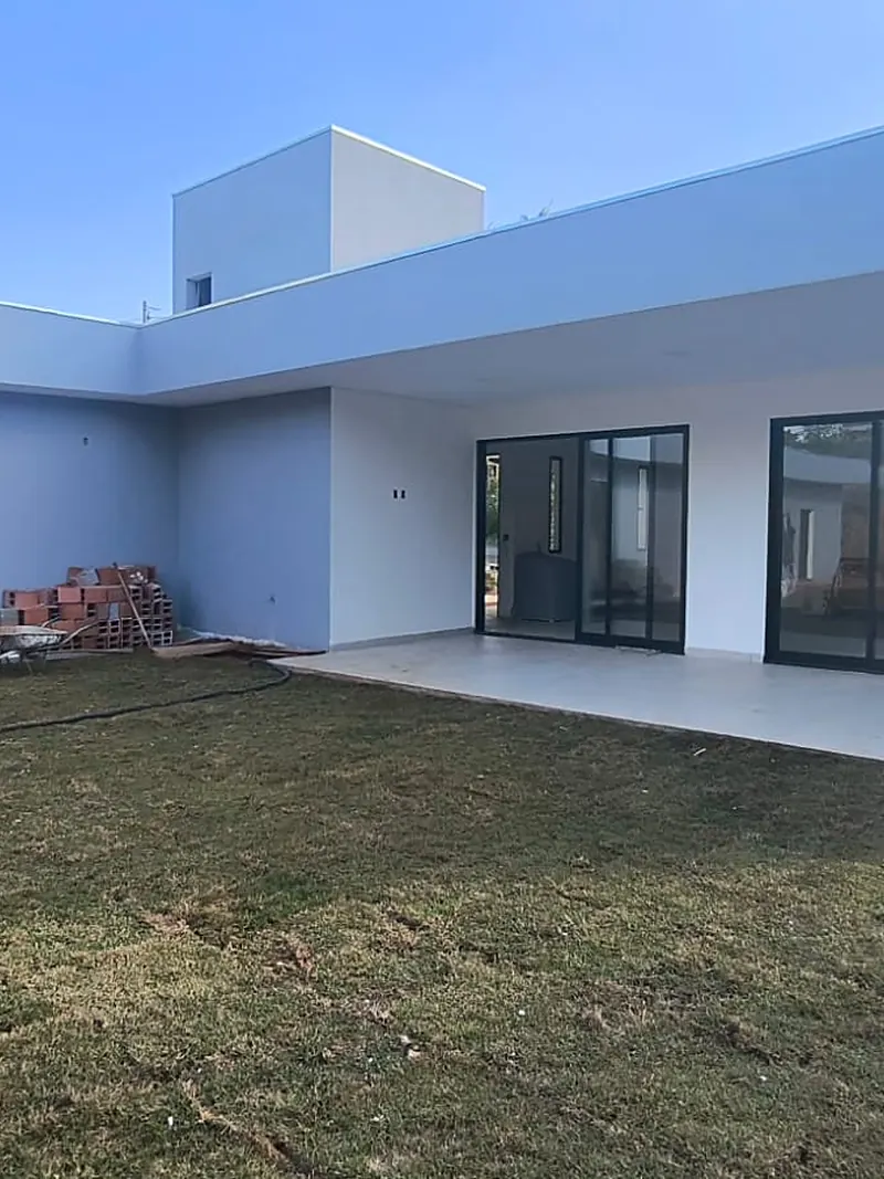 Casa térrea branca pronta, com portas de vidro abrindo para o gramado
